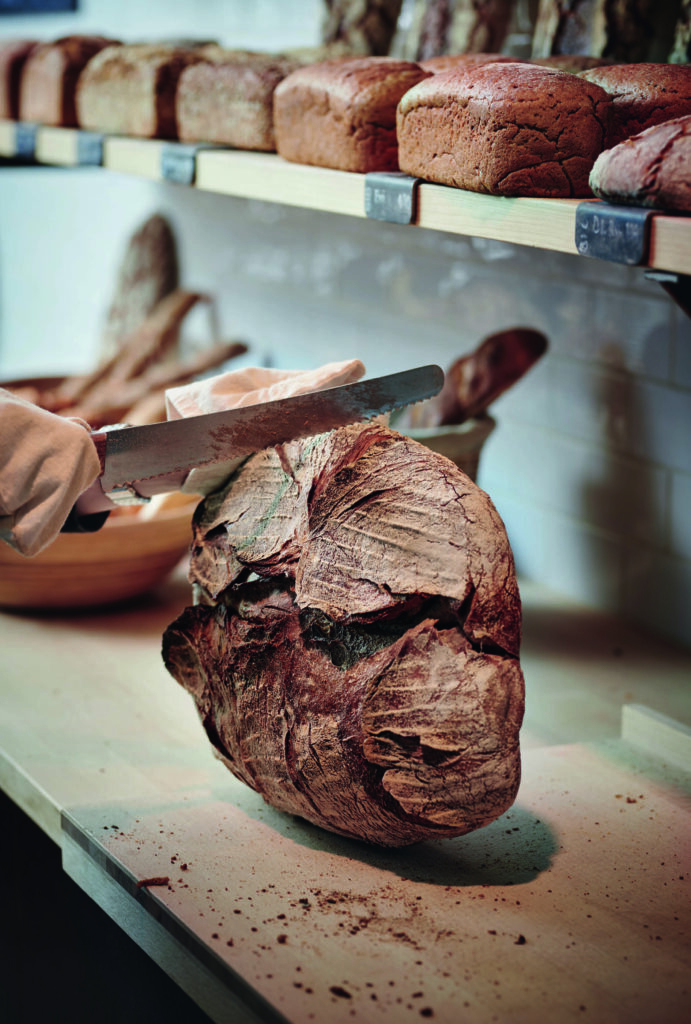 Een ambachtelijk brood wordt aangesneden in de bakkerij